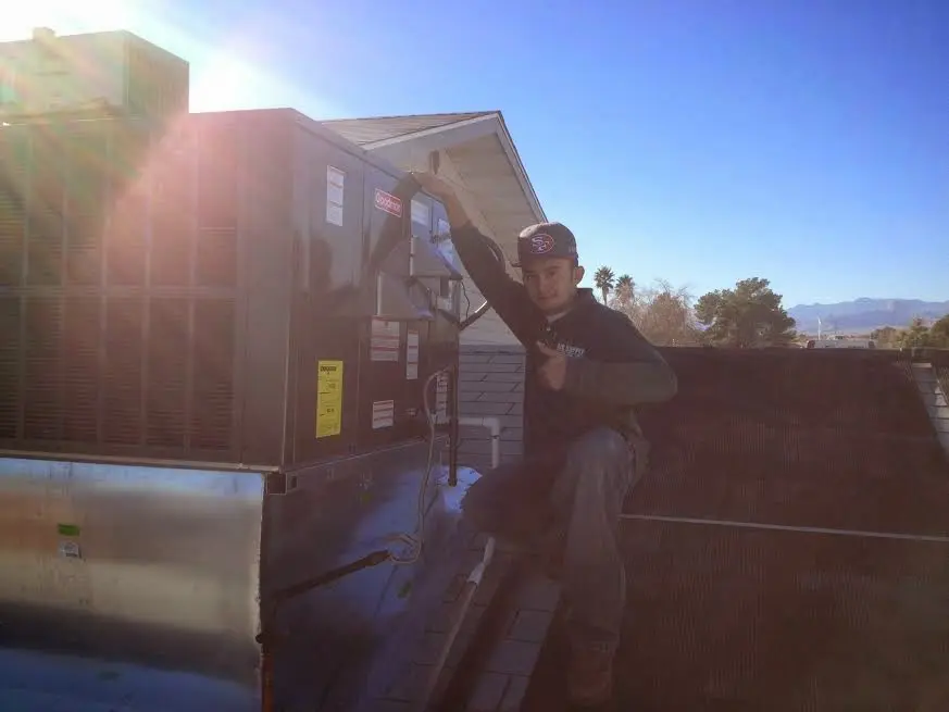 HVAC technician performing AC Tune-Up on a rooftop unit in Rigby